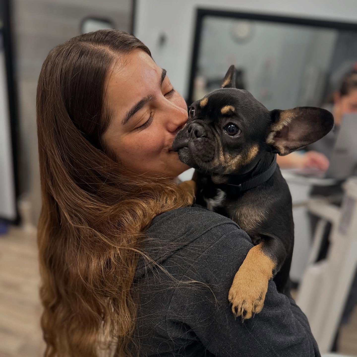 smiling woman holding French Bulldog puppy